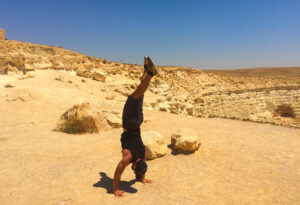 Man performing handstand in desert landscape.