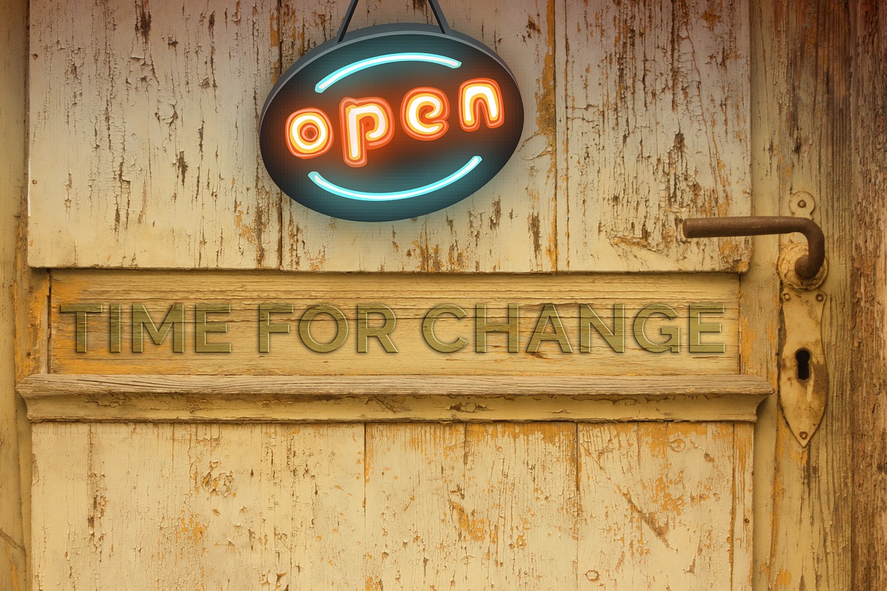 Neon "Open" sign on weathered door with "Time for Change" text.