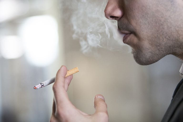 Man exhaling smoke while holding a cigarette.