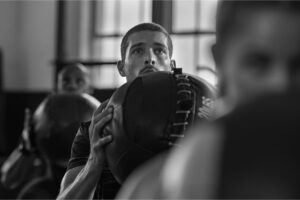 Focused boxer training with punching mitts in gym.