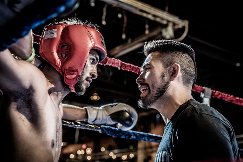 Boxers in ring, coach motivating athlete during match.