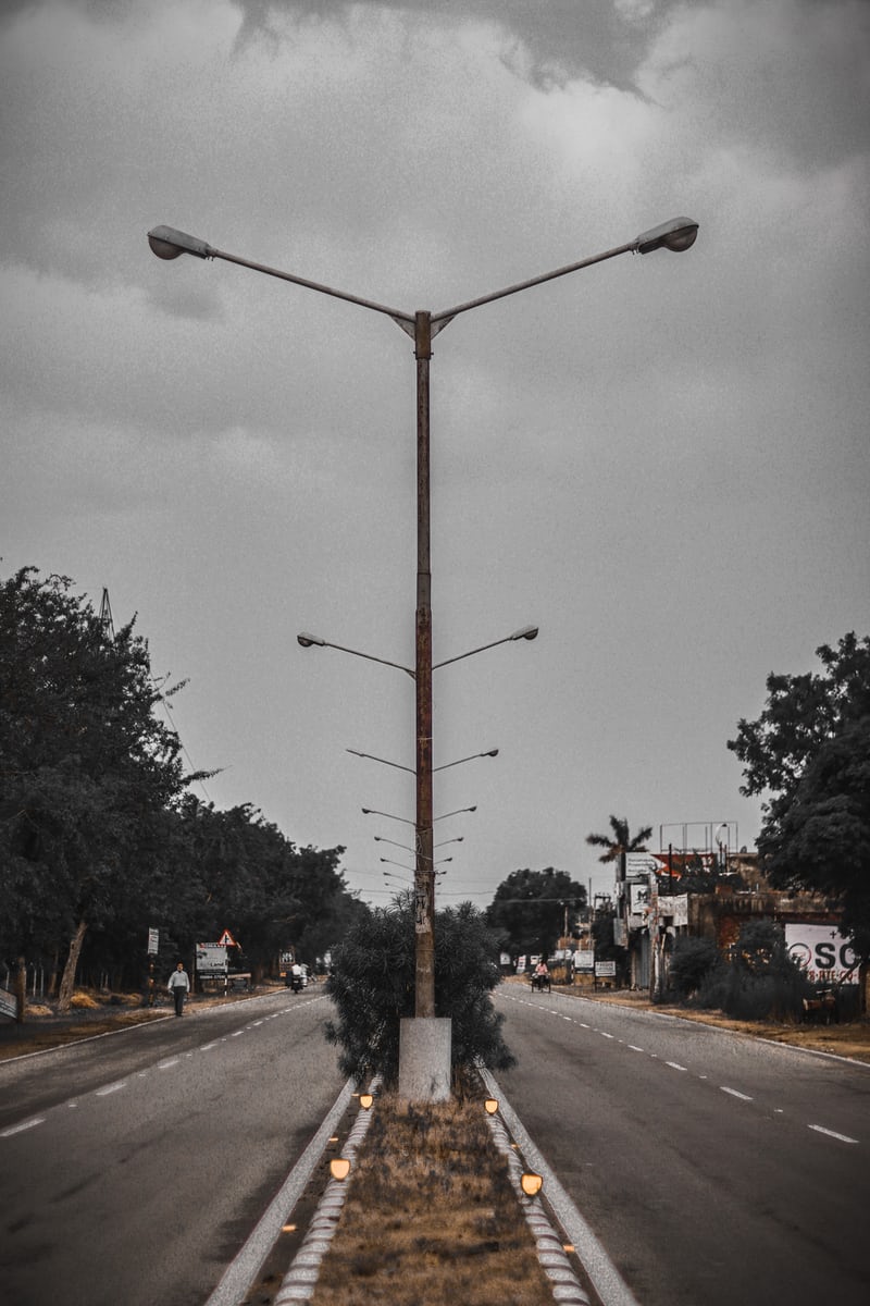 Moody street view with abandoned lampposts and cloudy sky.