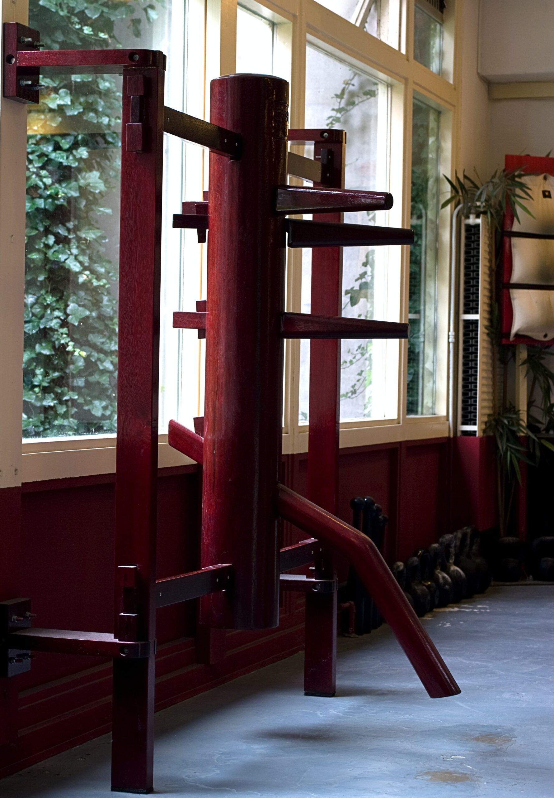 Traditional wooden Wing Chun dummy in martial arts studio.