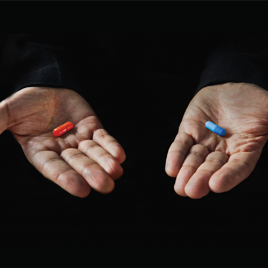 Hands presenting red and blue capsules against dark background.