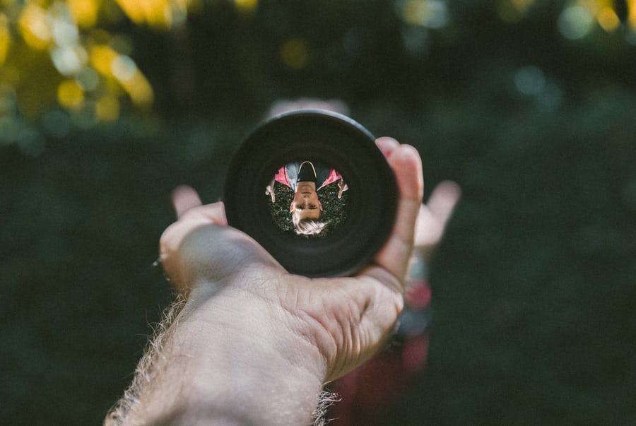 Person viewed through camera lens outdoors.