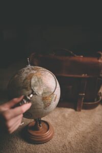 Hand adjusting vintage globe beside leather briefcase.