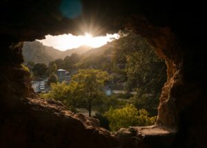 Sunset viewed through cave opening over mountains.