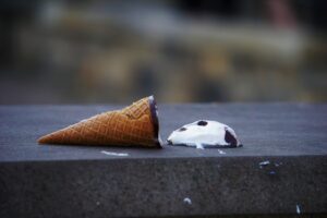 Dropped ice cream cone on concrete surface.