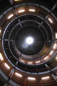 Spiral parking garage interior, illuminated by overhead lights.