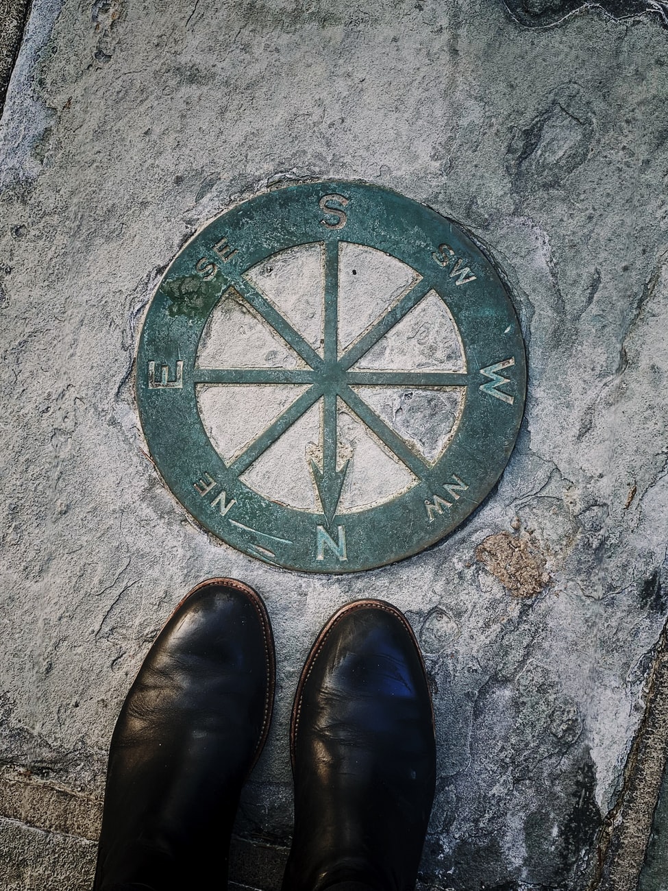 Feet above compass inlay on stone pavement.