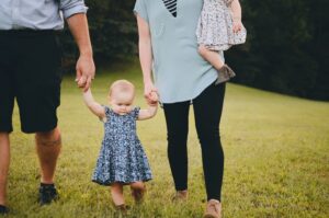 Parents and toddlers walking together on grass.