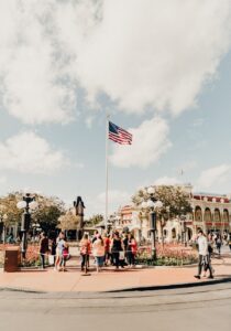 American flag over lively theme park entrance.