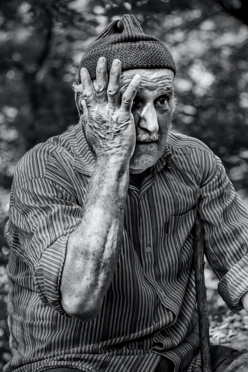 Elderly man with hand on face, black and white photo.