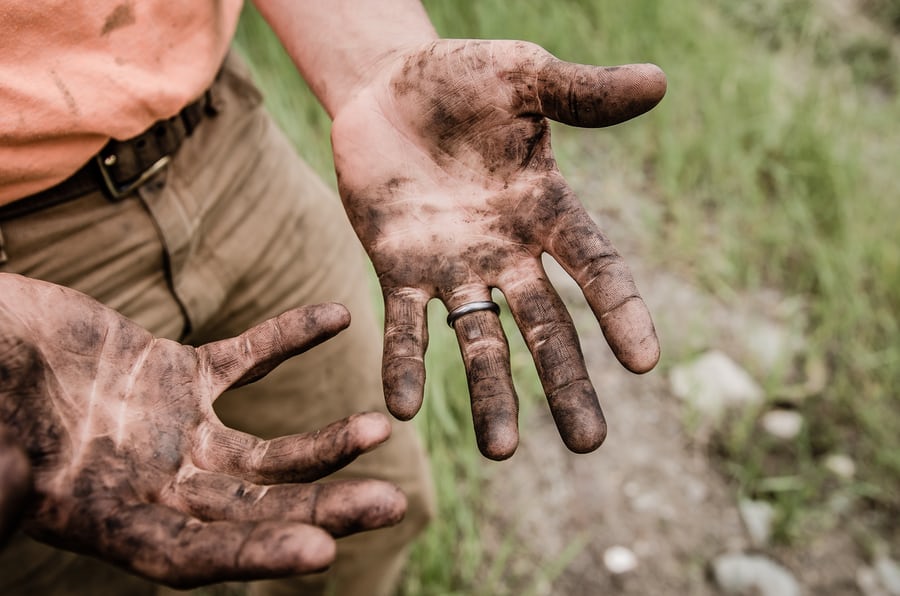 Man showing dirty hands outdoors