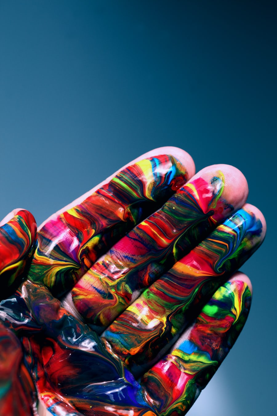 Hand covered in vibrant multicolored paint.