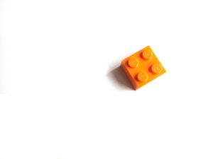 Single orange LEGO brick on white background.