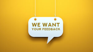 Hanging 'We Want Your Feedback' sign on yellow background.