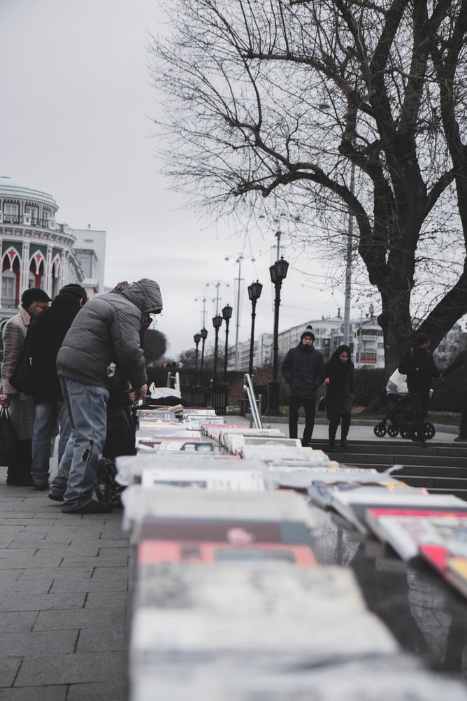 People browsing books at outdoor street market.