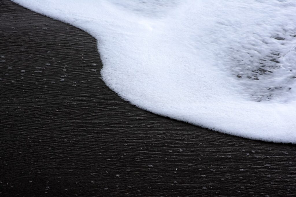 Foamy white wave on dark rippled water surface.