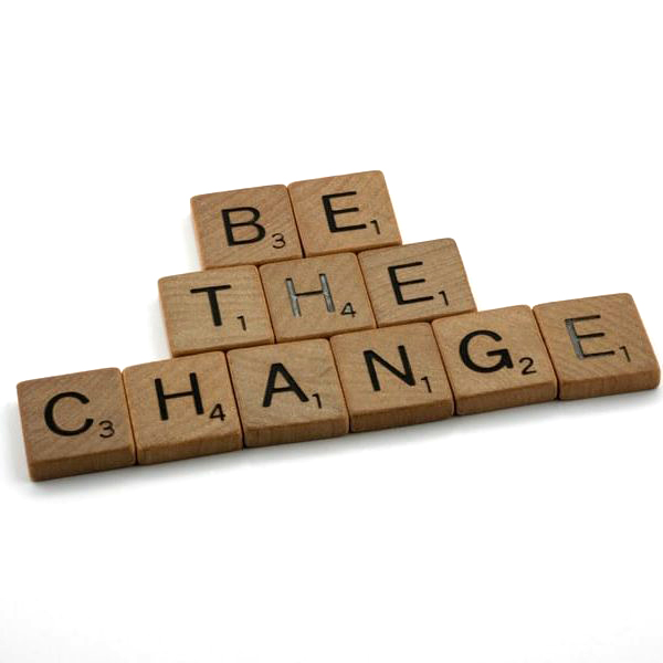 Scrabble tiles spelling "Be The Change" on white background.