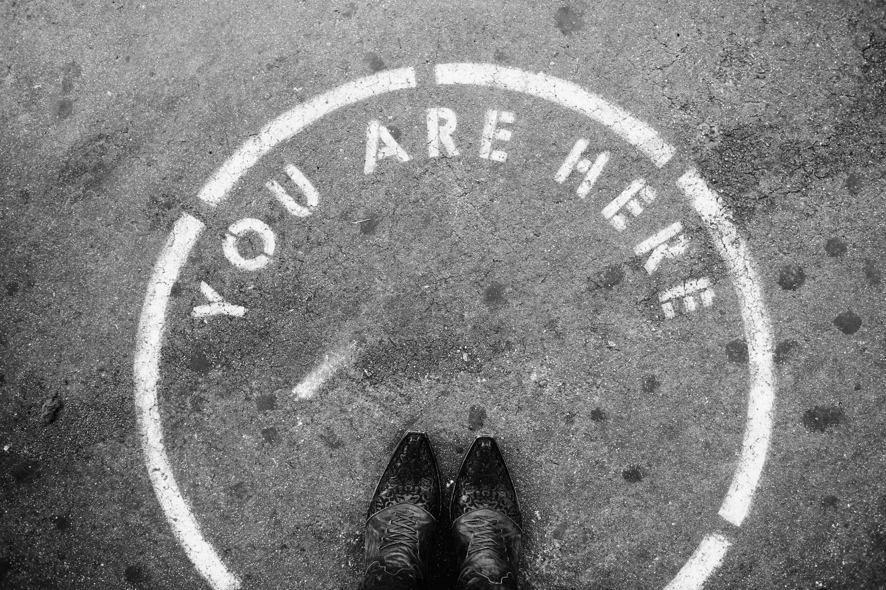 Person standing on "You Are Here" sidewalk marker.