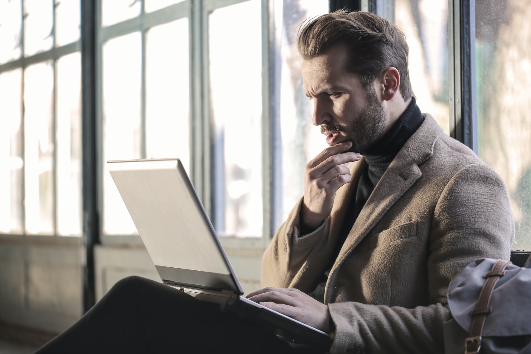 Man working on laptop in sunlit vintage room.