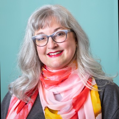 Smiling woman with glasses and colorful scarf.