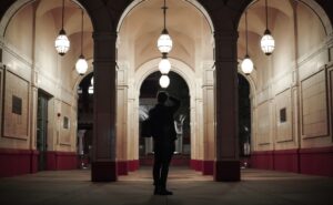 Person under archway with hanging lanterns at night.