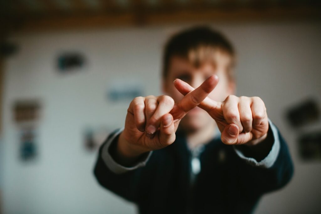 Person making an X sign with fingers.