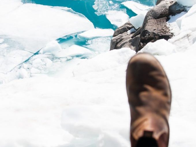 Boot overlooking icy glacier landscape.