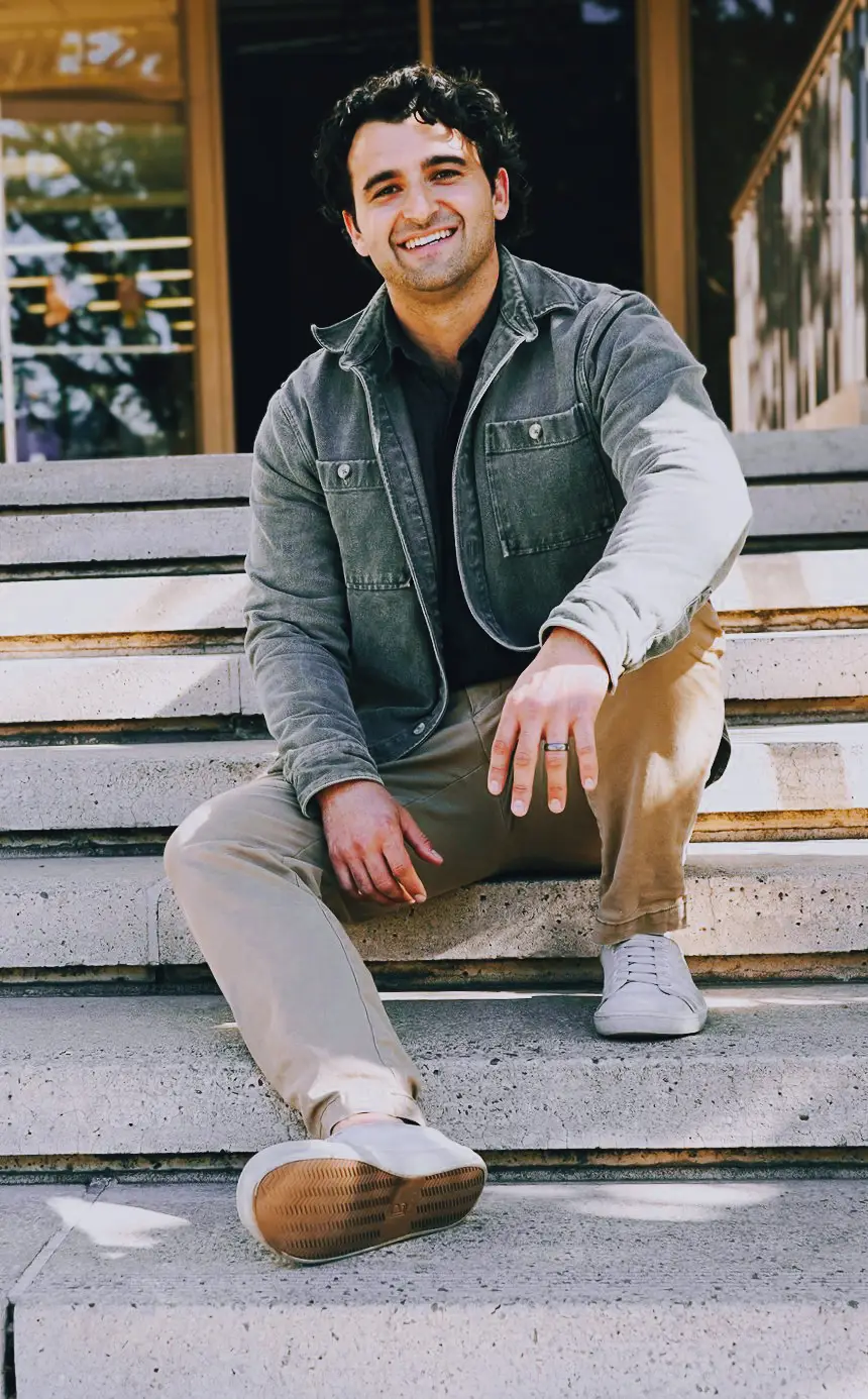 Smiling man sitting on steps in casual outfit