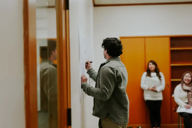 Man writing on whiteboard during workshop with spectators