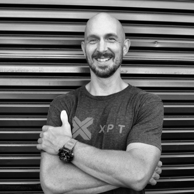 Smiling bald man in t-shirt leaning against metal shutters