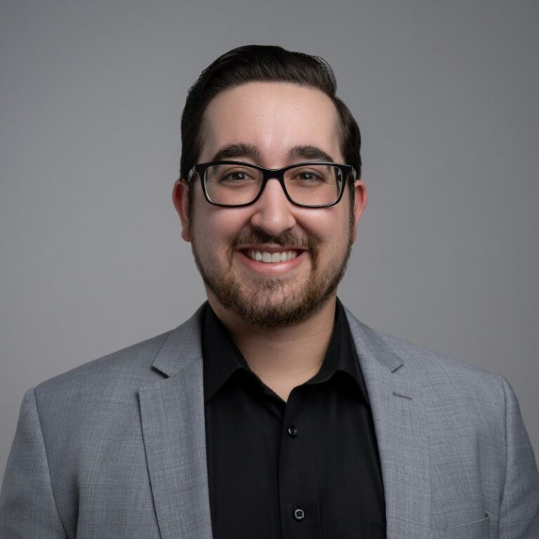 Smiling man in glasses and grey suit, professional headshot