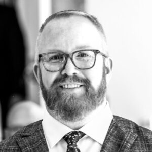 Smiling bearded man in glasses wearing a suit