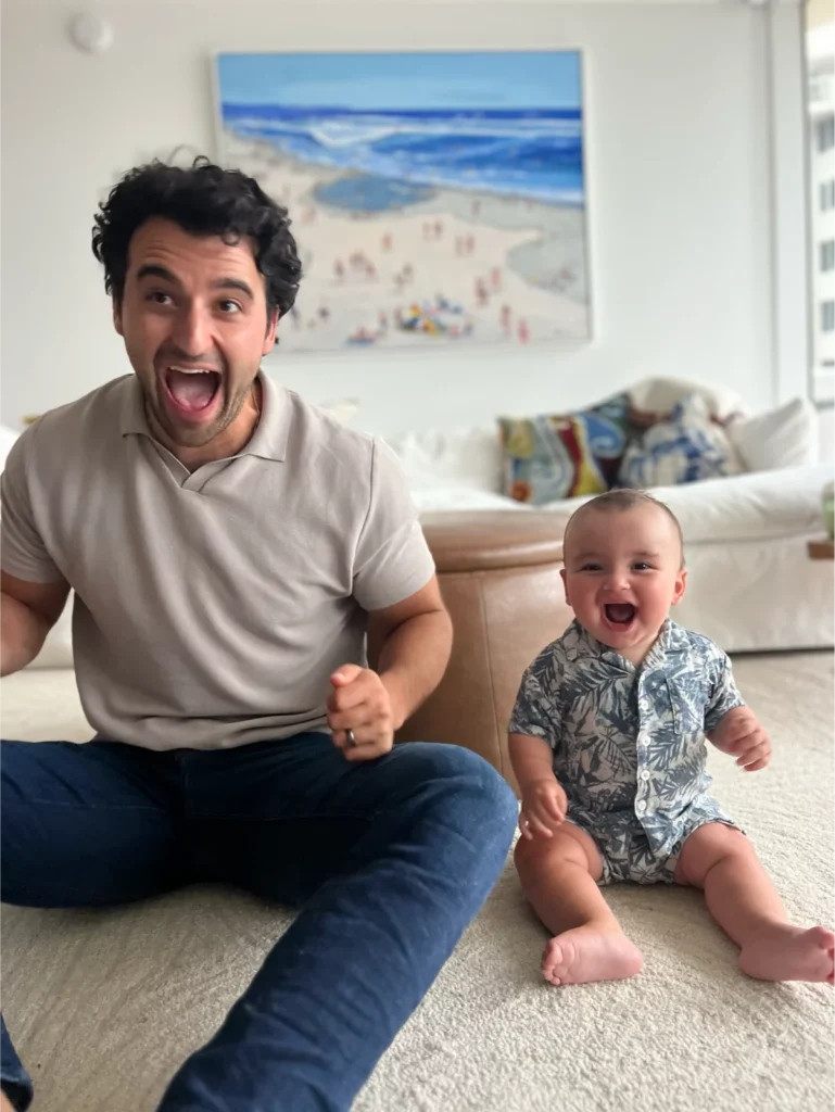 Joyful man and baby laughing together indoors