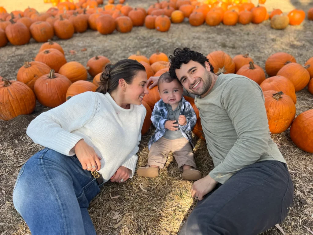 Family smiling among pumpkins at a pumpkin patch