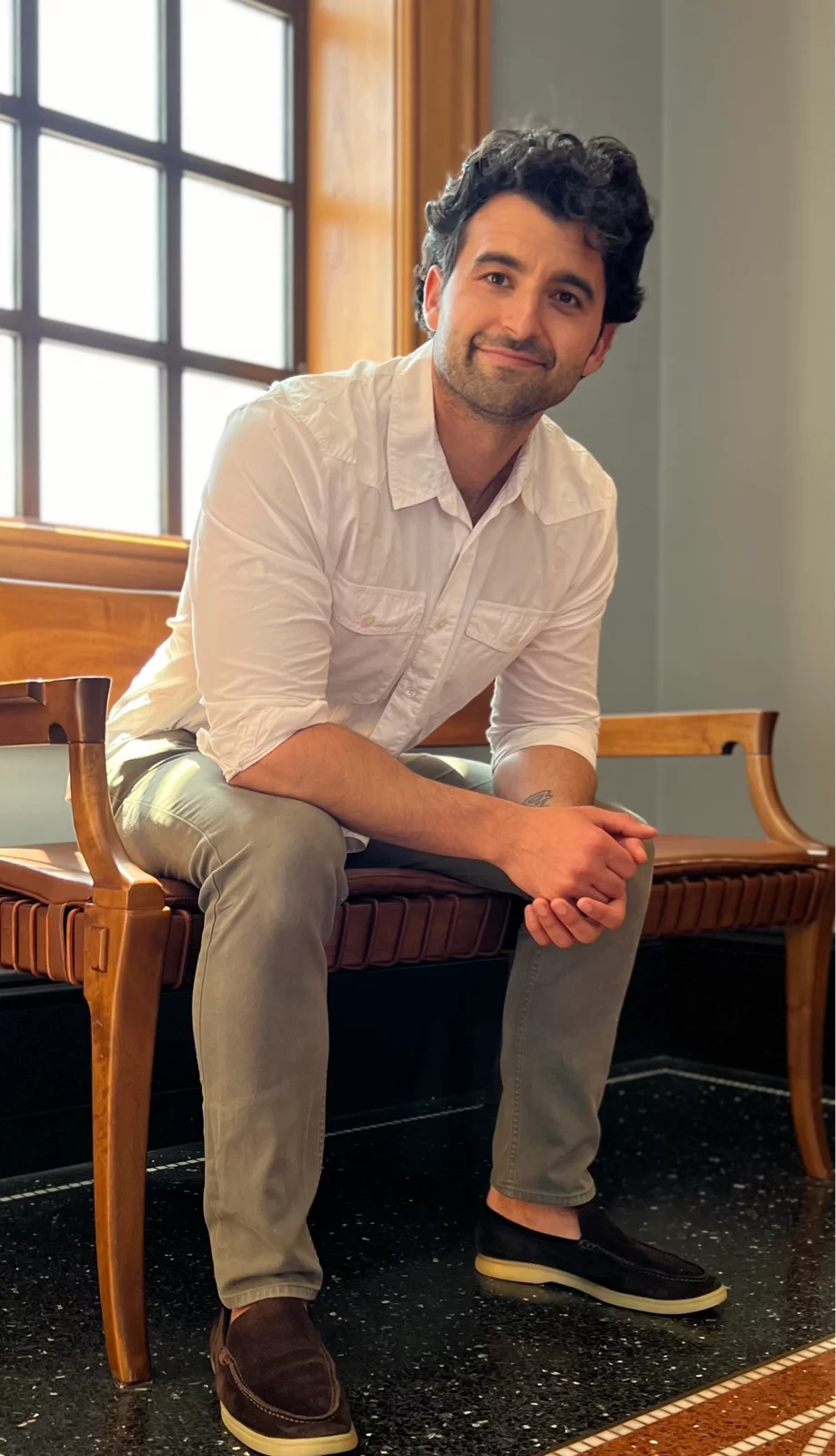 Smiling man seated on wooden bench indoors