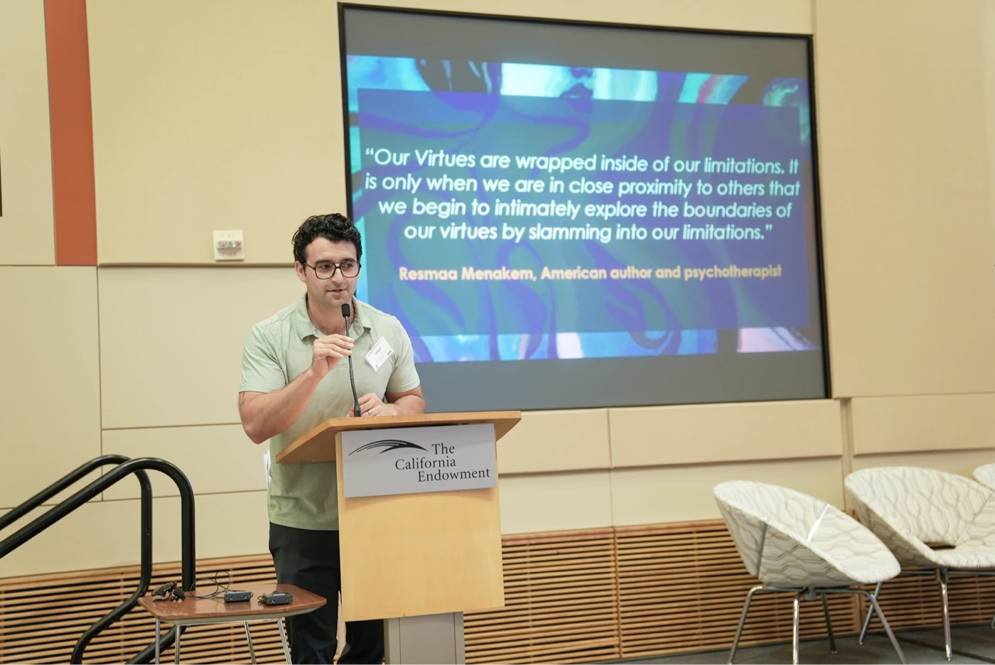 Man speaking at podium with quote projection in background