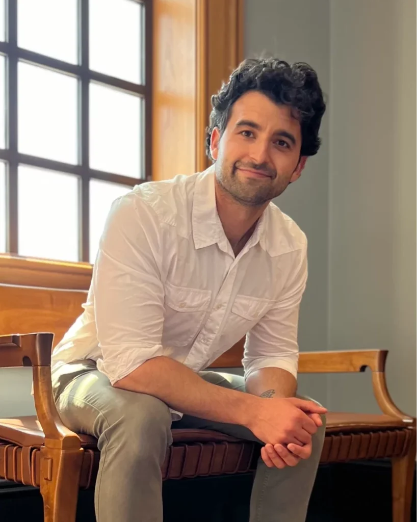 Man smiling in white shirt sitting by window