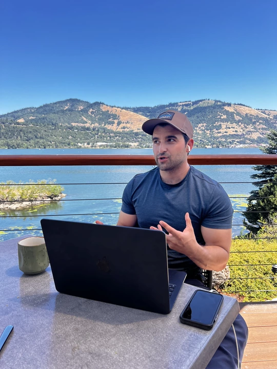 Man working on laptop at scenic lakeside terrace