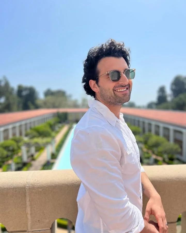 Man smiling in sunglasses at sunny balcony garden