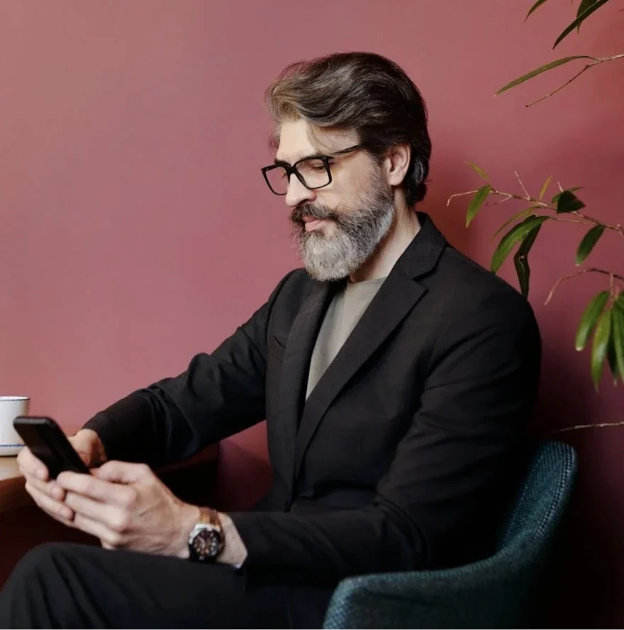 Man in suit using smartphone in pink room