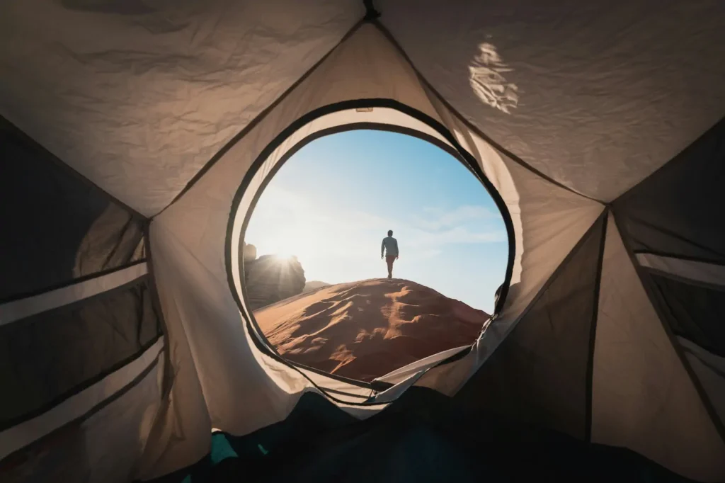 Person on hill seen from tent entrance at sunrise