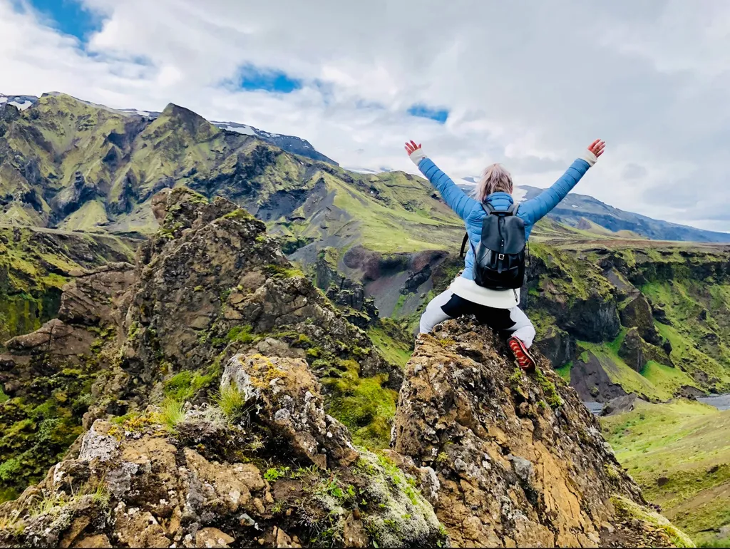 Person celebrating atop a rugged mountain landscape