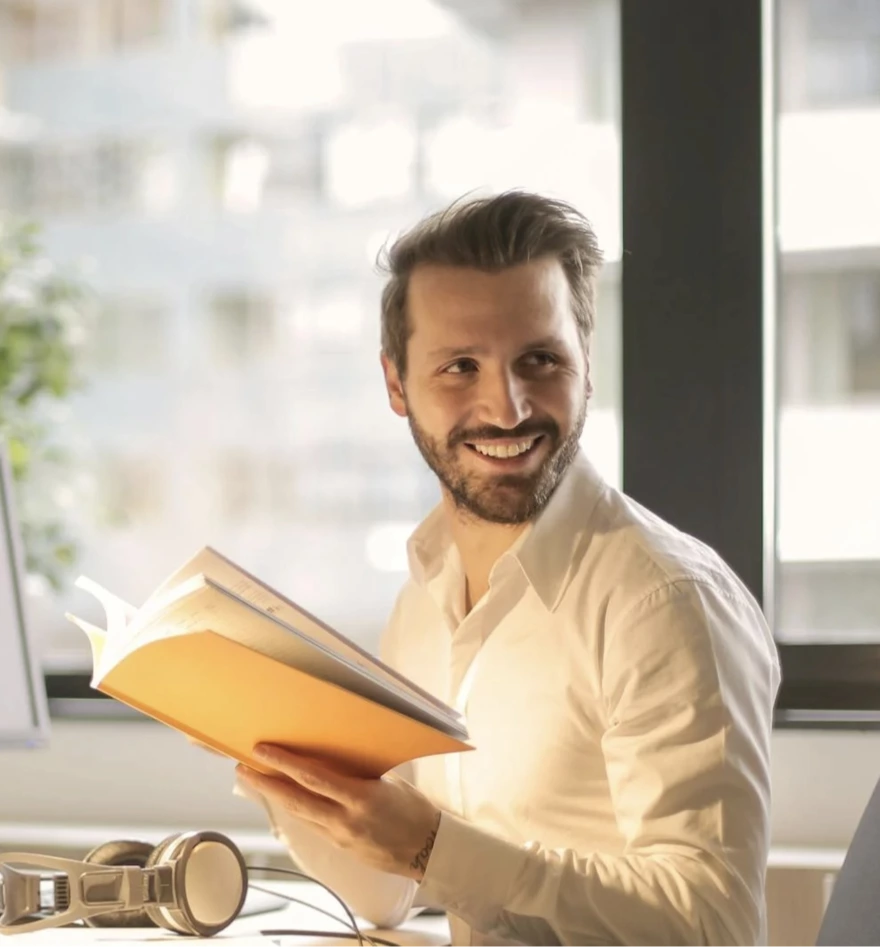 Smiling man reading book in sunny office