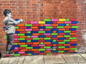Street art of boy building colorful brick wall