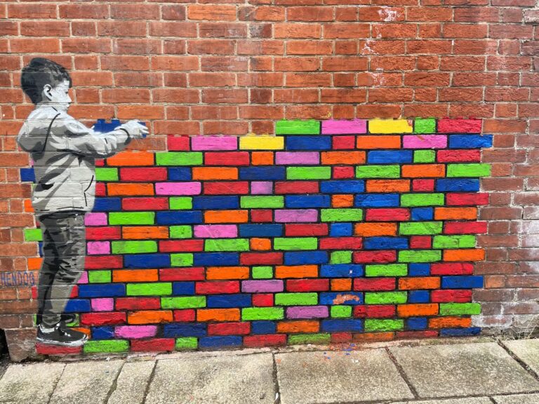 Street art of boy building colorful brick wall